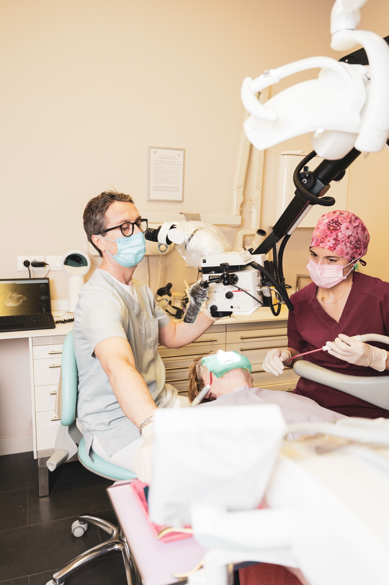 Il Dott. Ballerini esegue un trattamento canalare al microscopio operatorio, assistito da una collaboratrice